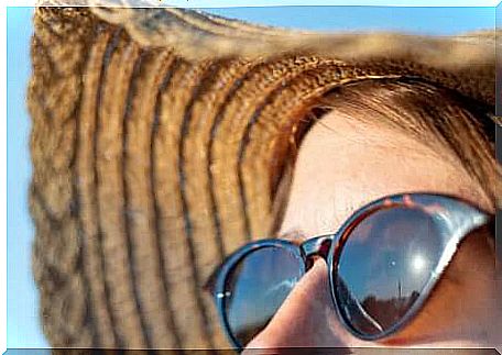 The face of a woman in the sun with glasses and a hat for protection from solar radiation.